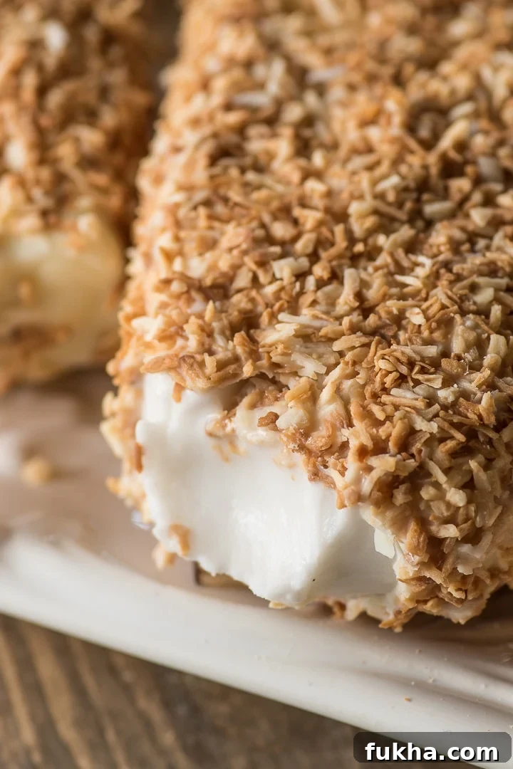 close up shot of the inside of a creamy coconut popsicle surrounded by a toasted coconut shell 