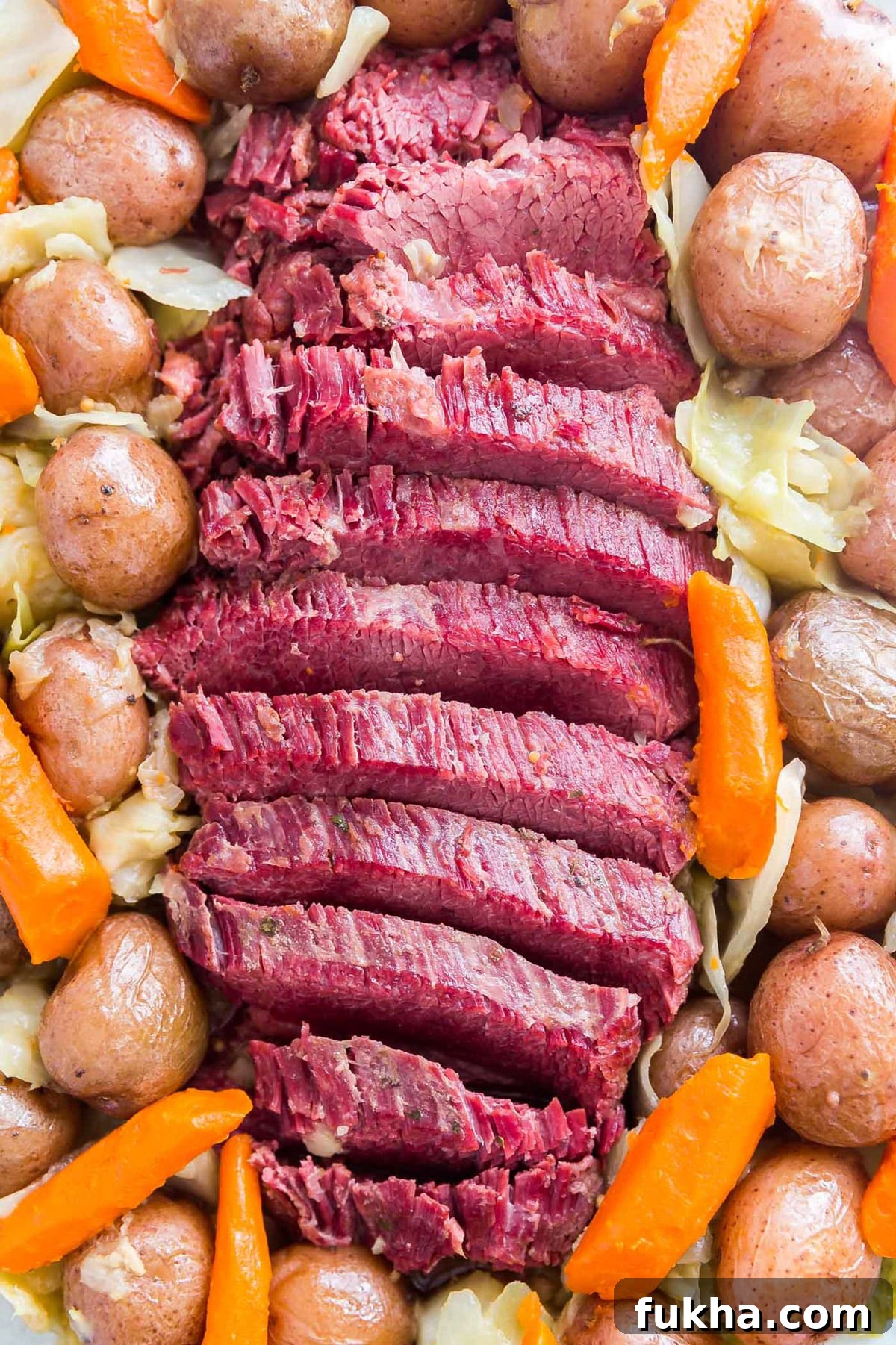 An overhead image of sliced corned beef surrounded by veggies.