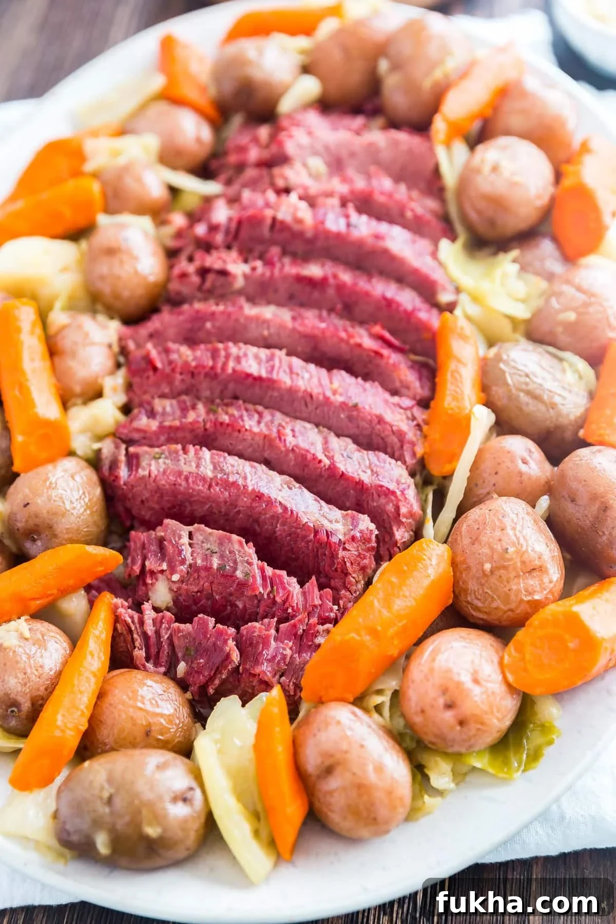 sliced corned beef on a large platter surrounded by vegetables