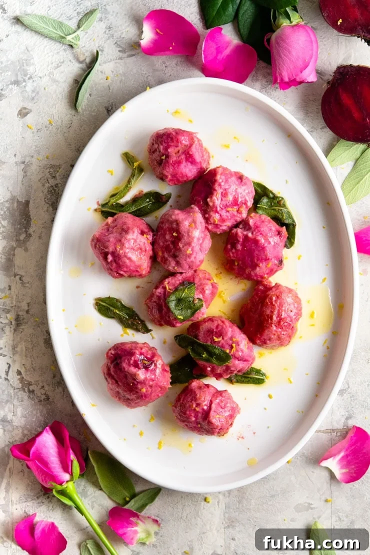 An overhead shot of beetroot ricotta gnudi on an oval plate with sage and butter