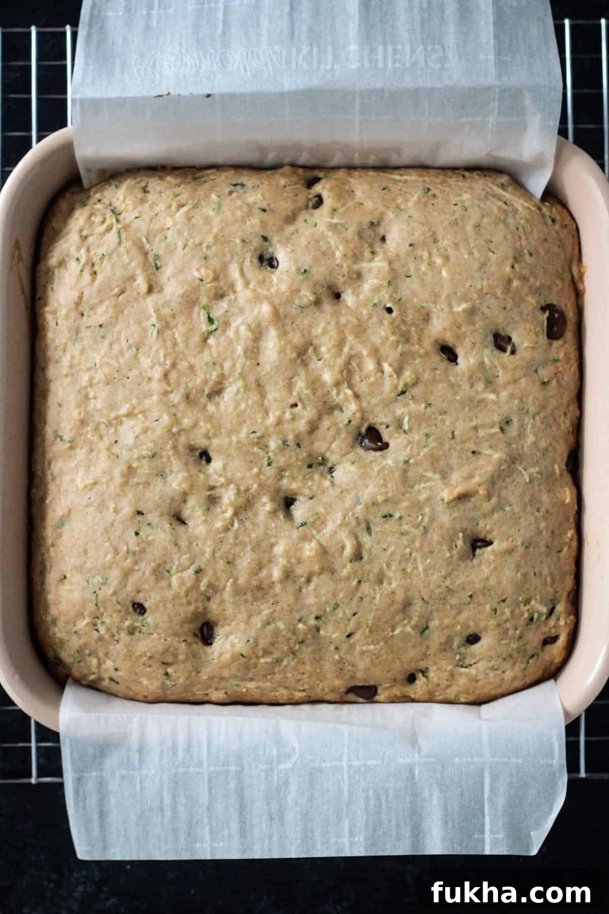 Baked chocolate chip zucchini cake in a square baking dish.