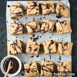 Squares of chocolate chip zucchini cake drizzled in chocolate sauce.