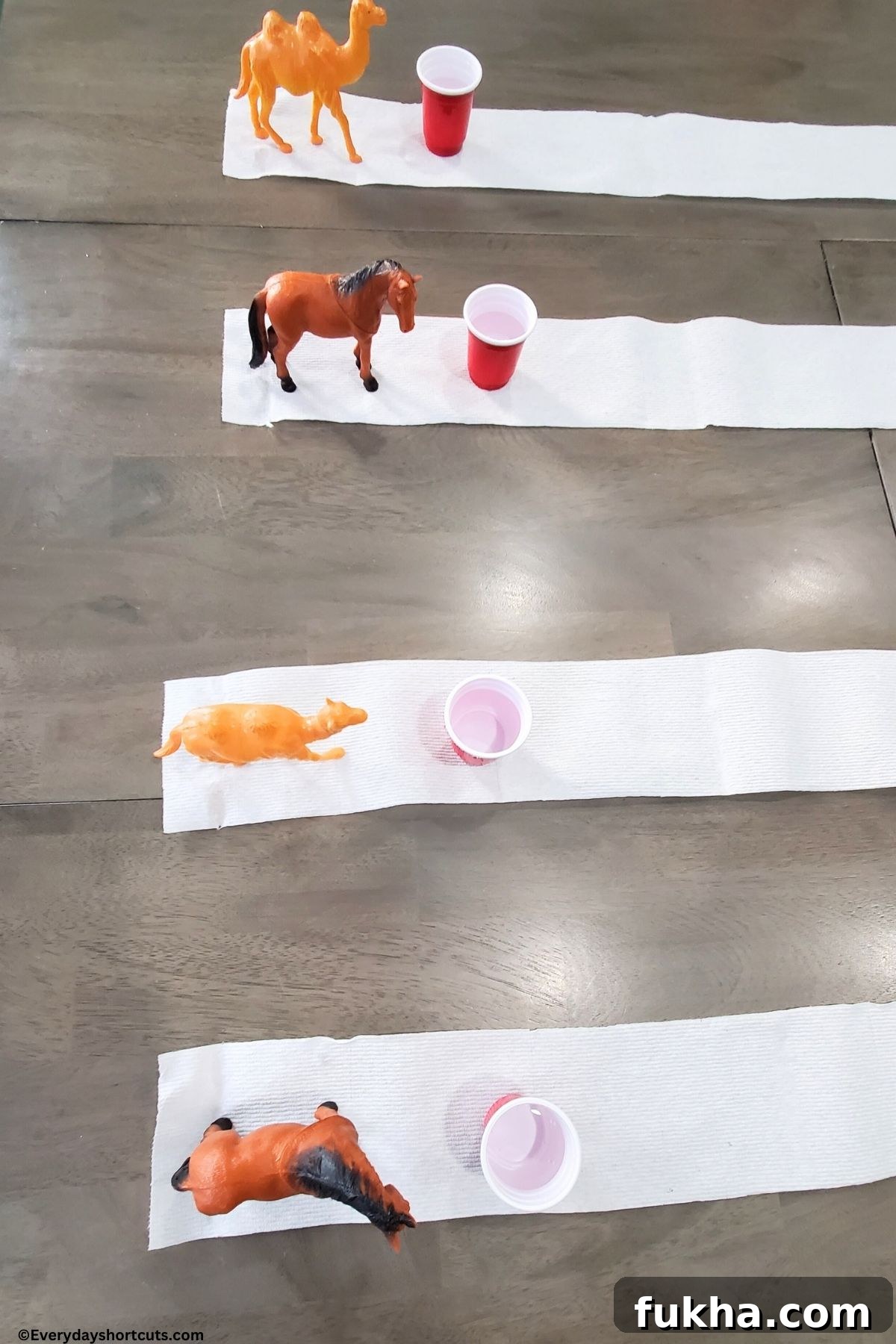 plastic farm animals on toilet paper with a shot glass of water
