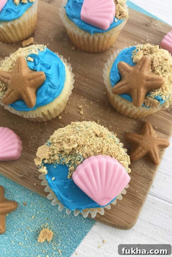 seashell topped beach style cupcakes on a wooden table 