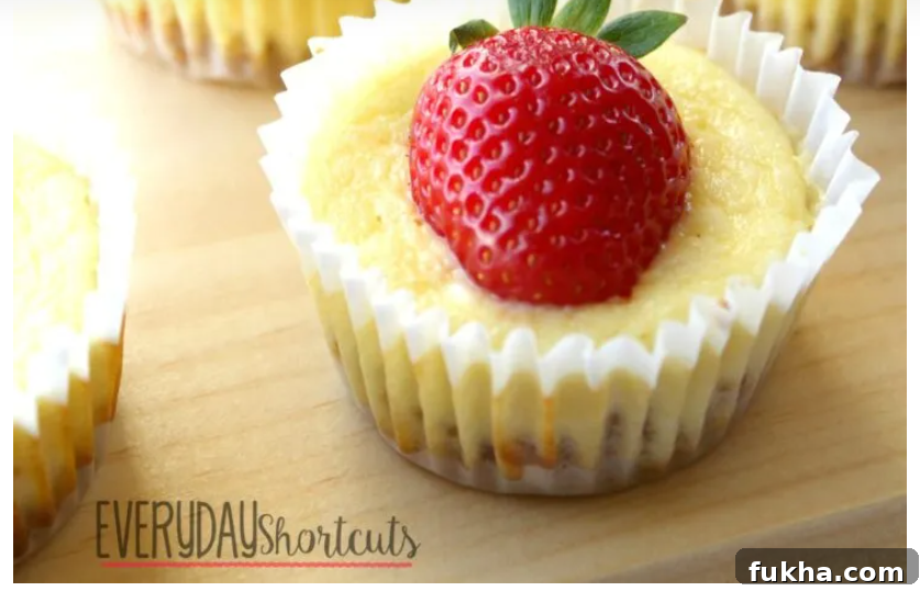 side view of a cheesecake cupcake with a strawberry sitting on top on a wooden table