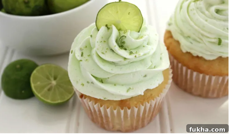 key lime cupcakes sitting on wooden table with key limes sliced in half sitting by the cupcakes