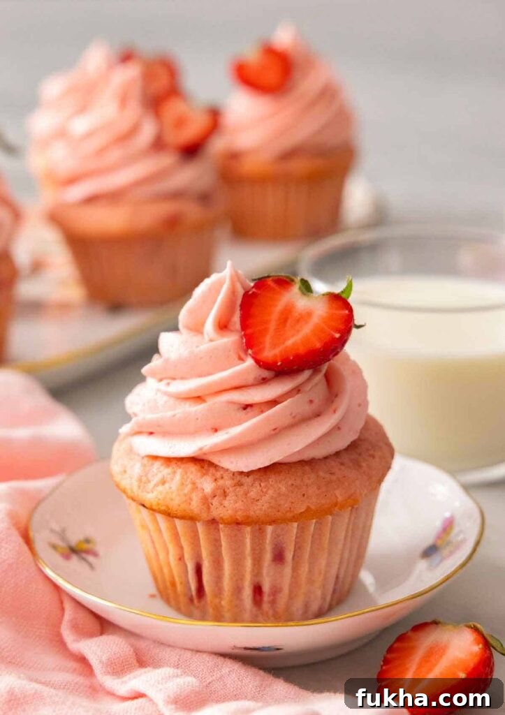 plate with a strawberry cupcake topped with a fresh sliced strawberry
