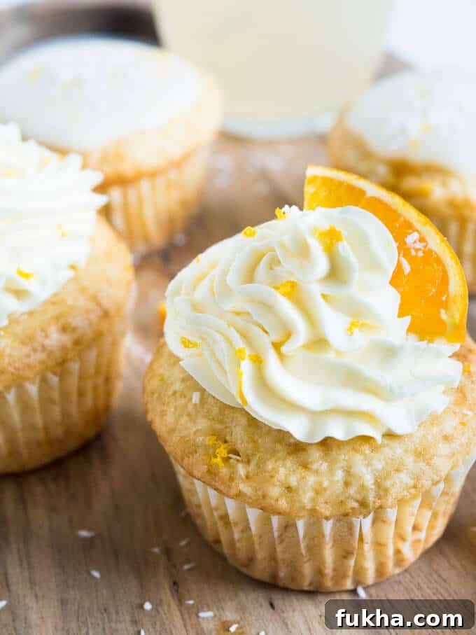 orange cupcake with a orange slice on top of frosting on wooden table 