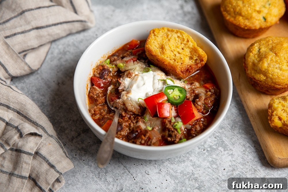Slow-Cooker Beef Chili Recipe with Rich Smoky Flavor 7 Bowl of chili with jalapeno cheddar cornbread muffins alongside.