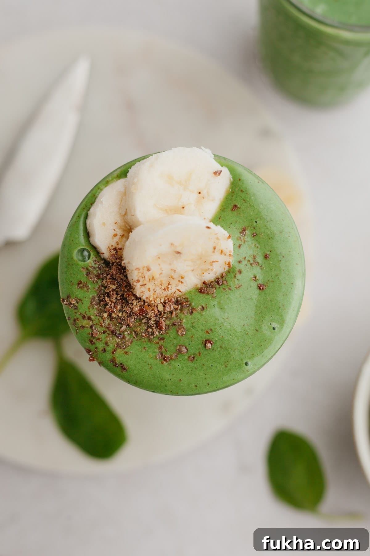Overhead shot of spinach banana smoothie topped with sliced bananas