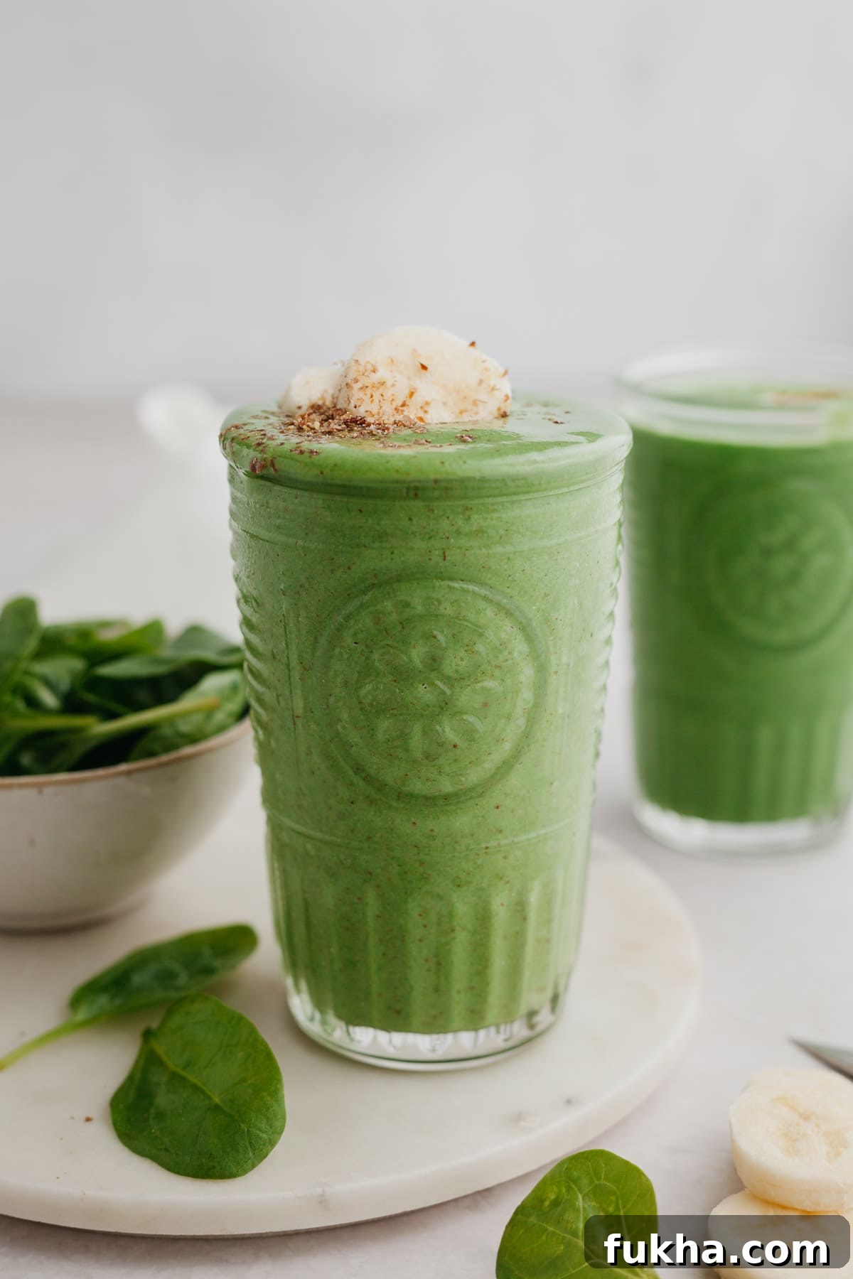 Glass of green smoothie topped with banana slices