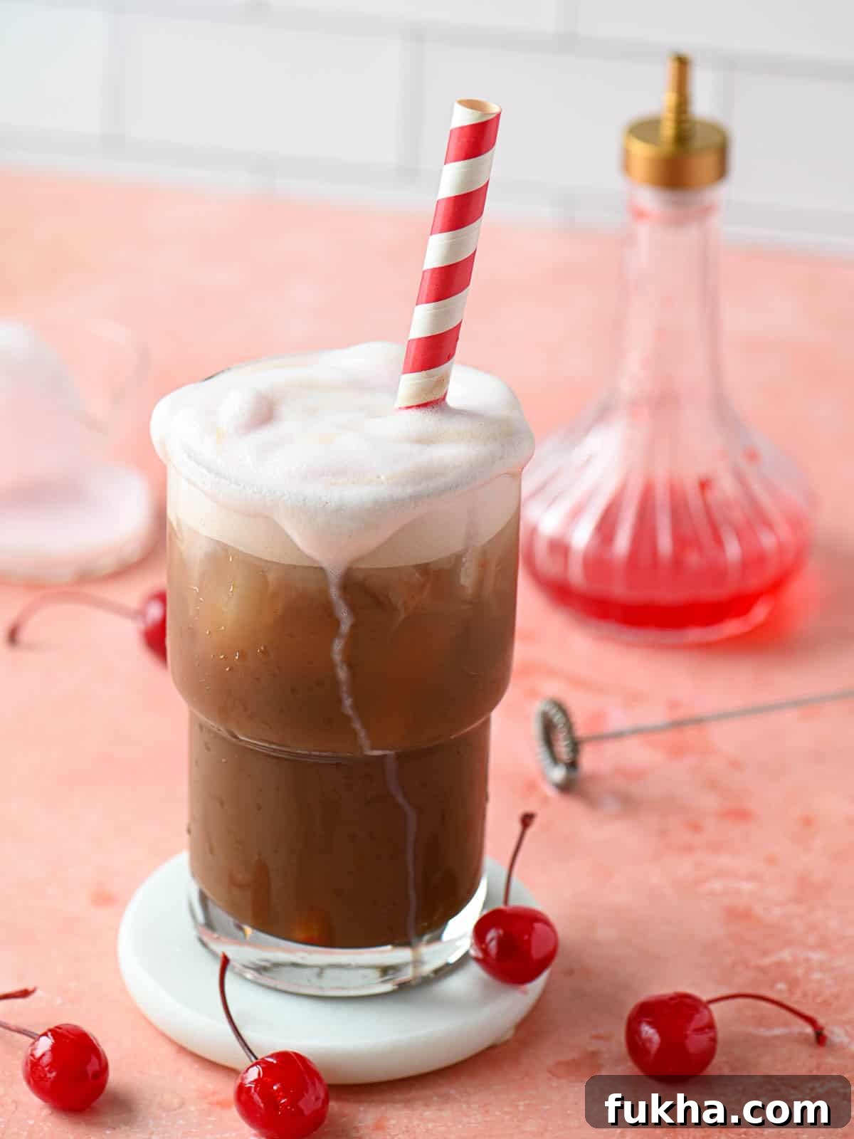Cherry Americola: Cherry Coffee Drink Recipe 2 A cherry americola drink with cherry cold foam dripping down in a clear glass.