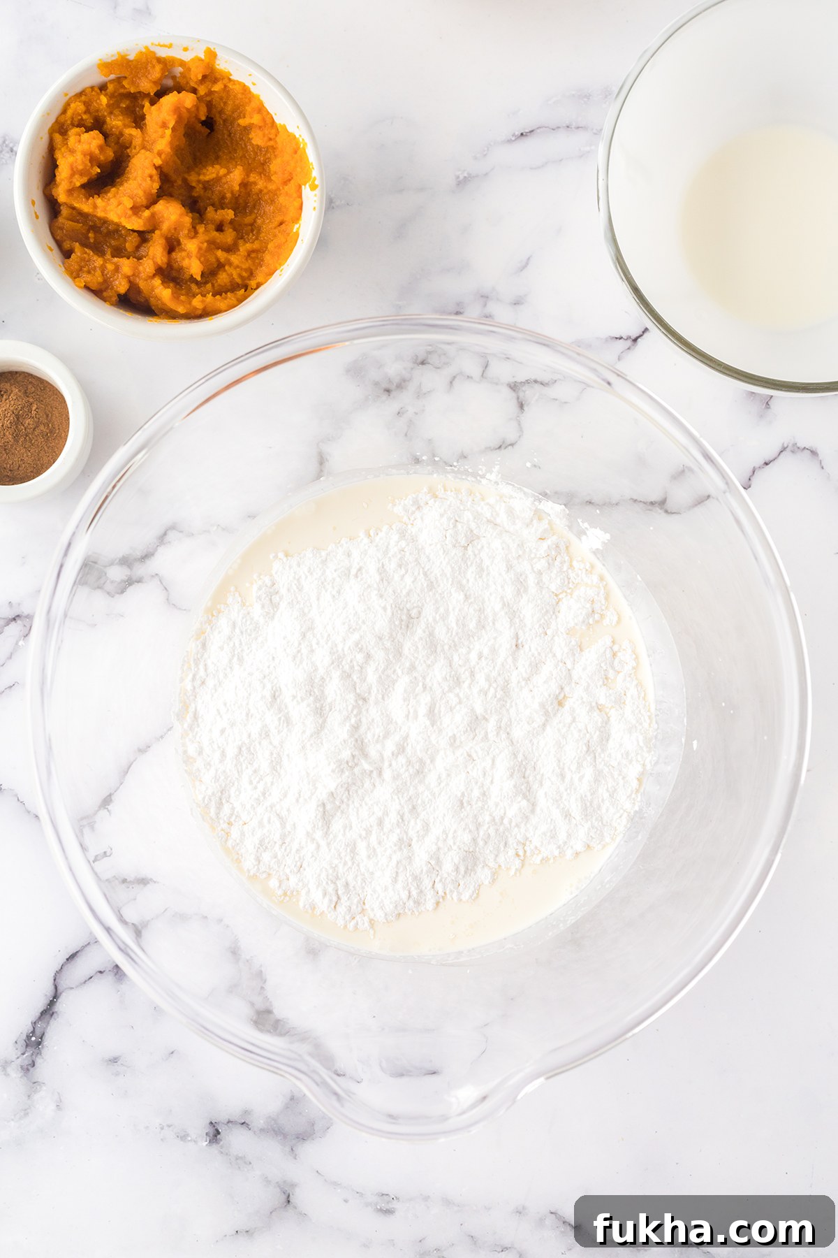 Heavy cream and powdered sugar in glass mixing bowl.