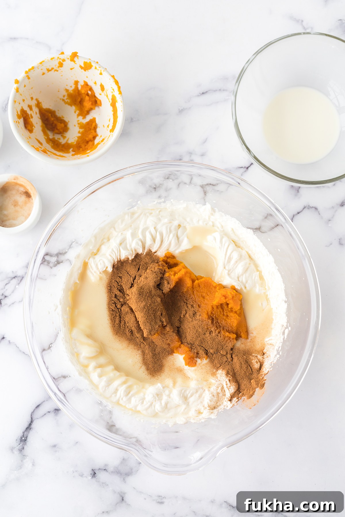 Sweetened condensed milk, pumpkin puré, and cinnamon added to wet ingredients in mixing bowl.