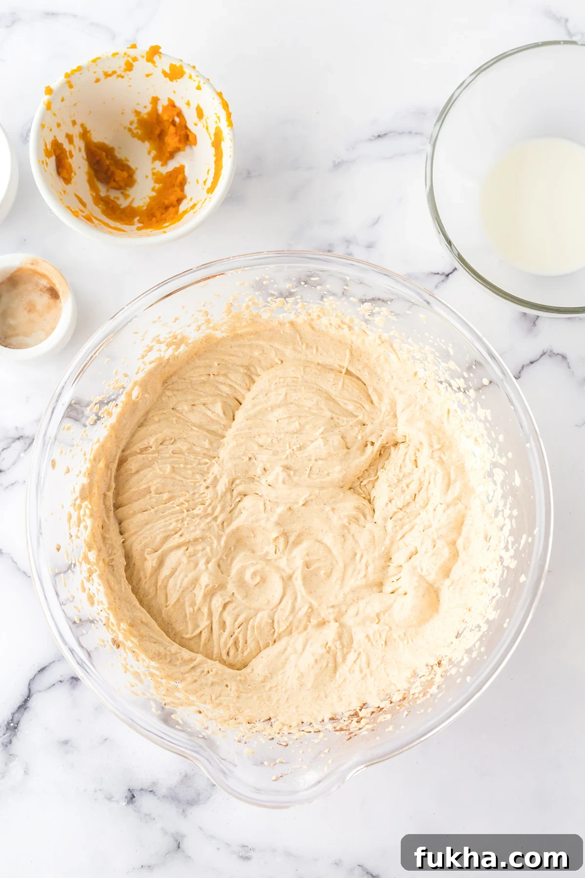 Pumpkin ice cream mixture in glass mixing bowl.
