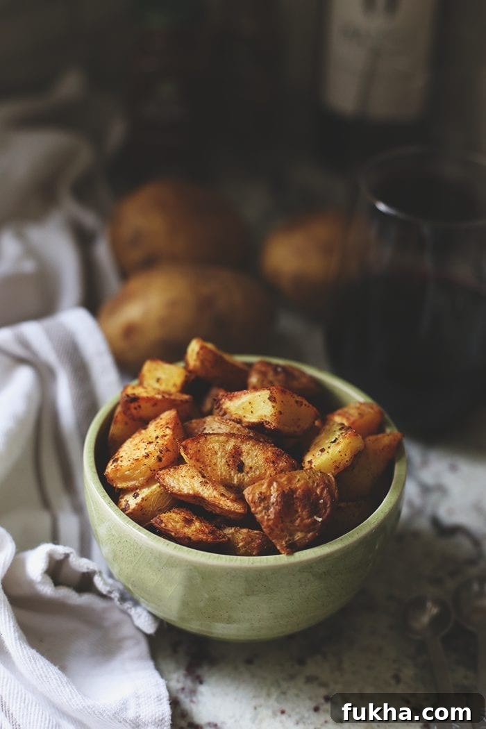 Crispy Roasted Potatoes: Oven and Air Fryer Methods 2 crispy roasted potatoes in a green bowl on the counter.