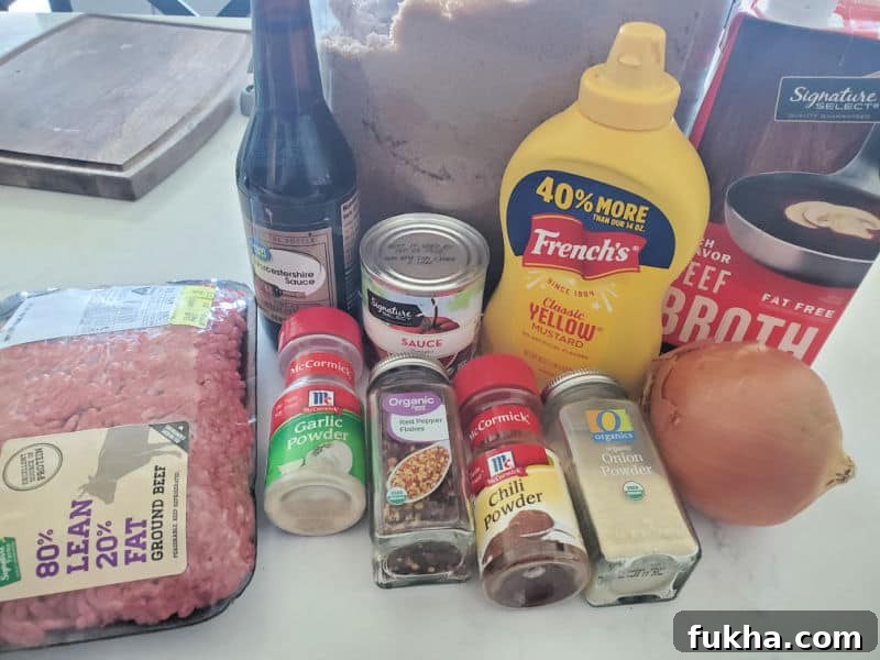 ground beef, garlic powder, chili powder, onion powder, onion, mustard, tomato sauce, brown sugar, and beef broth on a white counter 