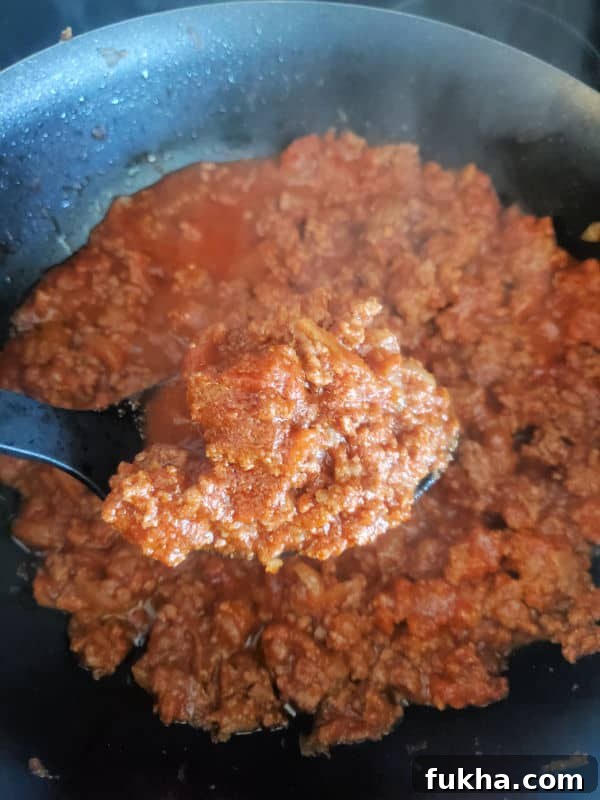 spoon holding ground beef mixture over a skillet