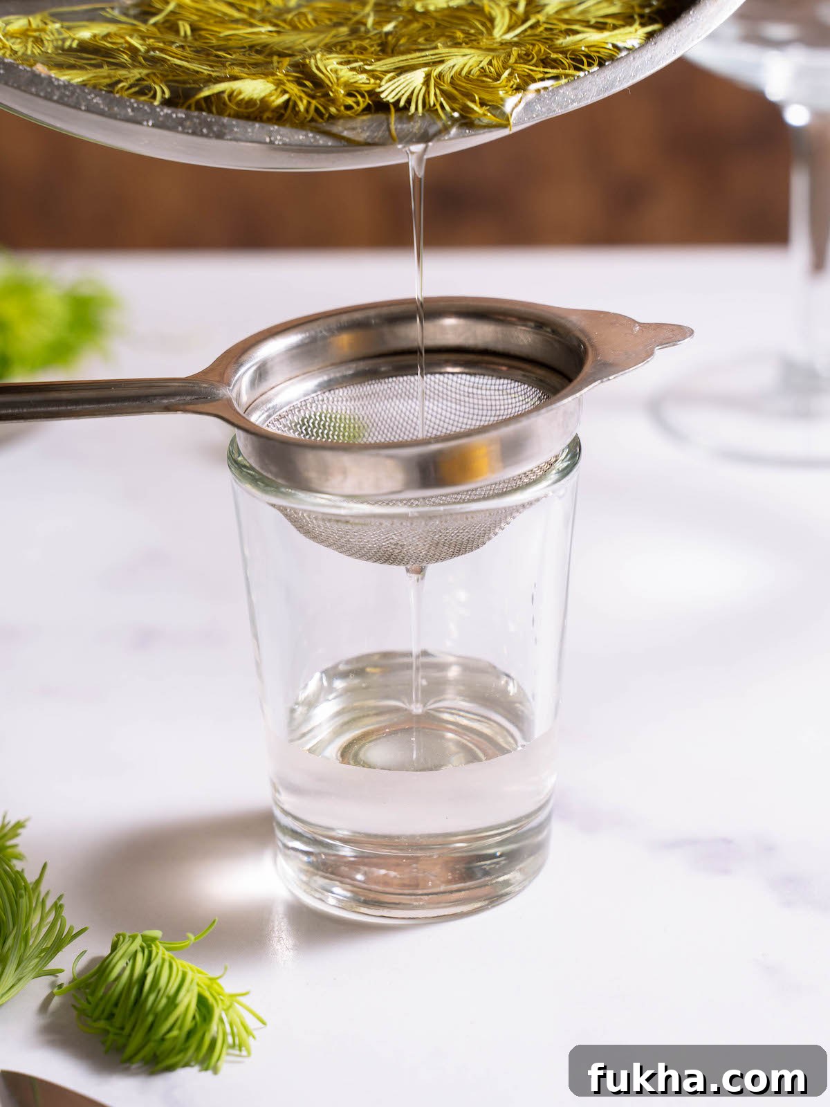 Straining fir tip syrup into a glass
