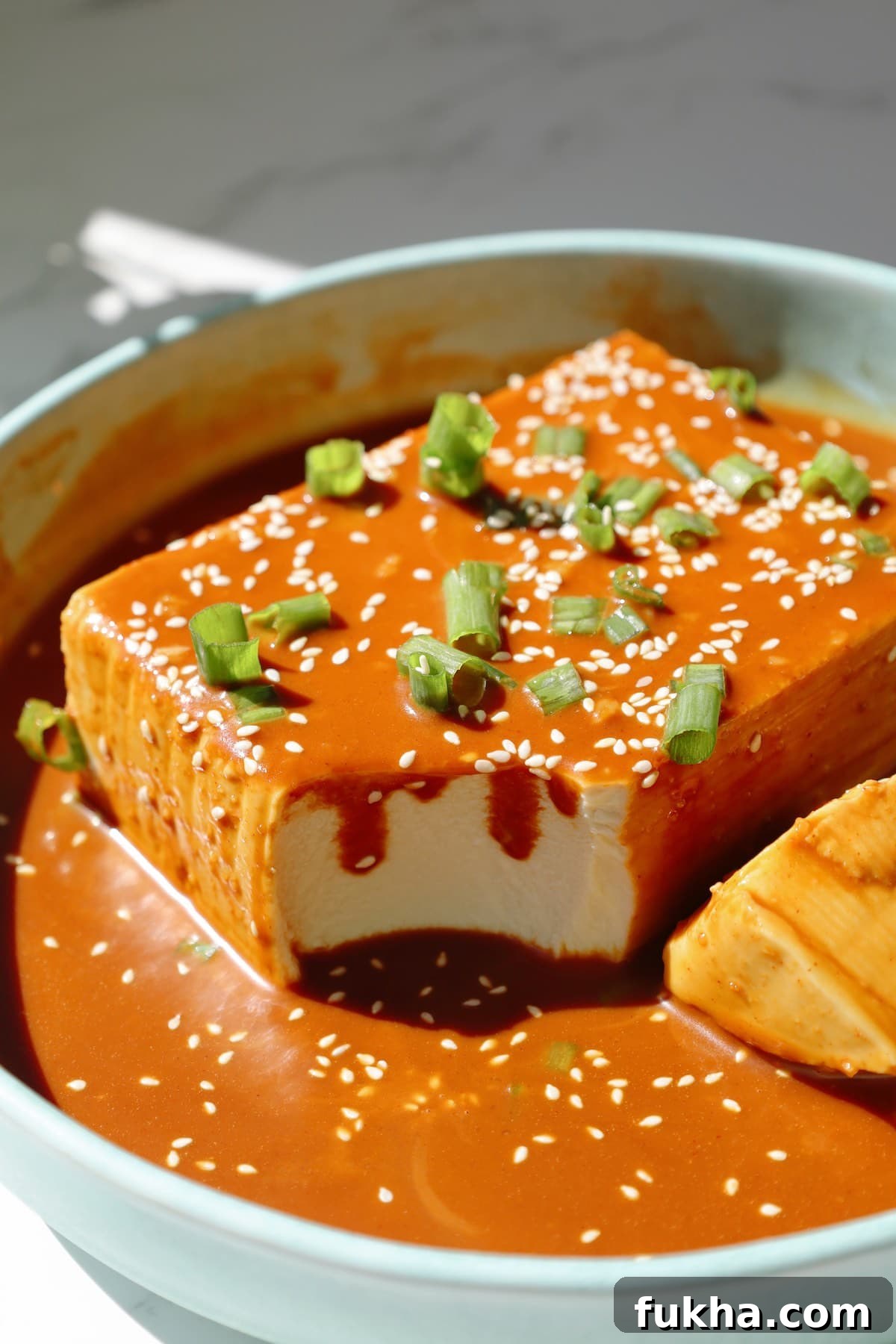 Step five: garnish the tofu with scallions and sesame seeds before serving.