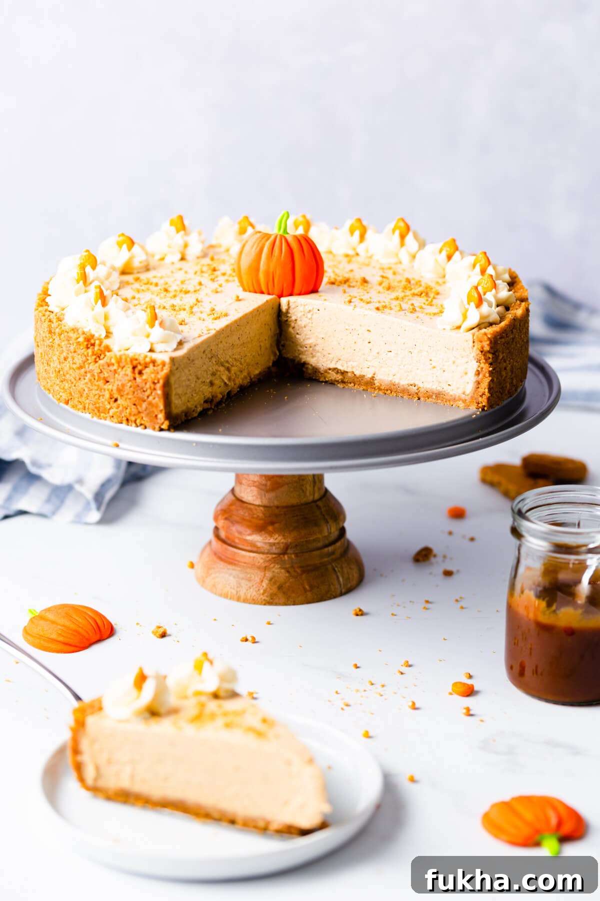 straight ahead angle of a no bake pumpkin cheesecake on a small cake stand with couple of pieces cut out