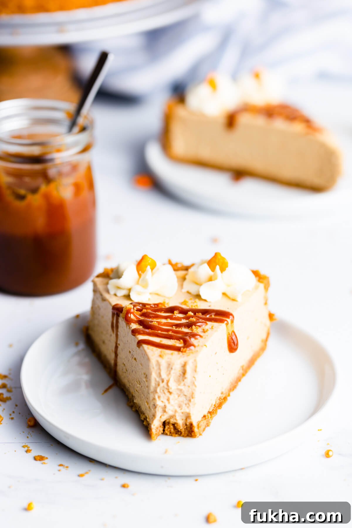 straight ahead super close up at a single slice of pumpkin cheesecake drizzled with caramel sauce