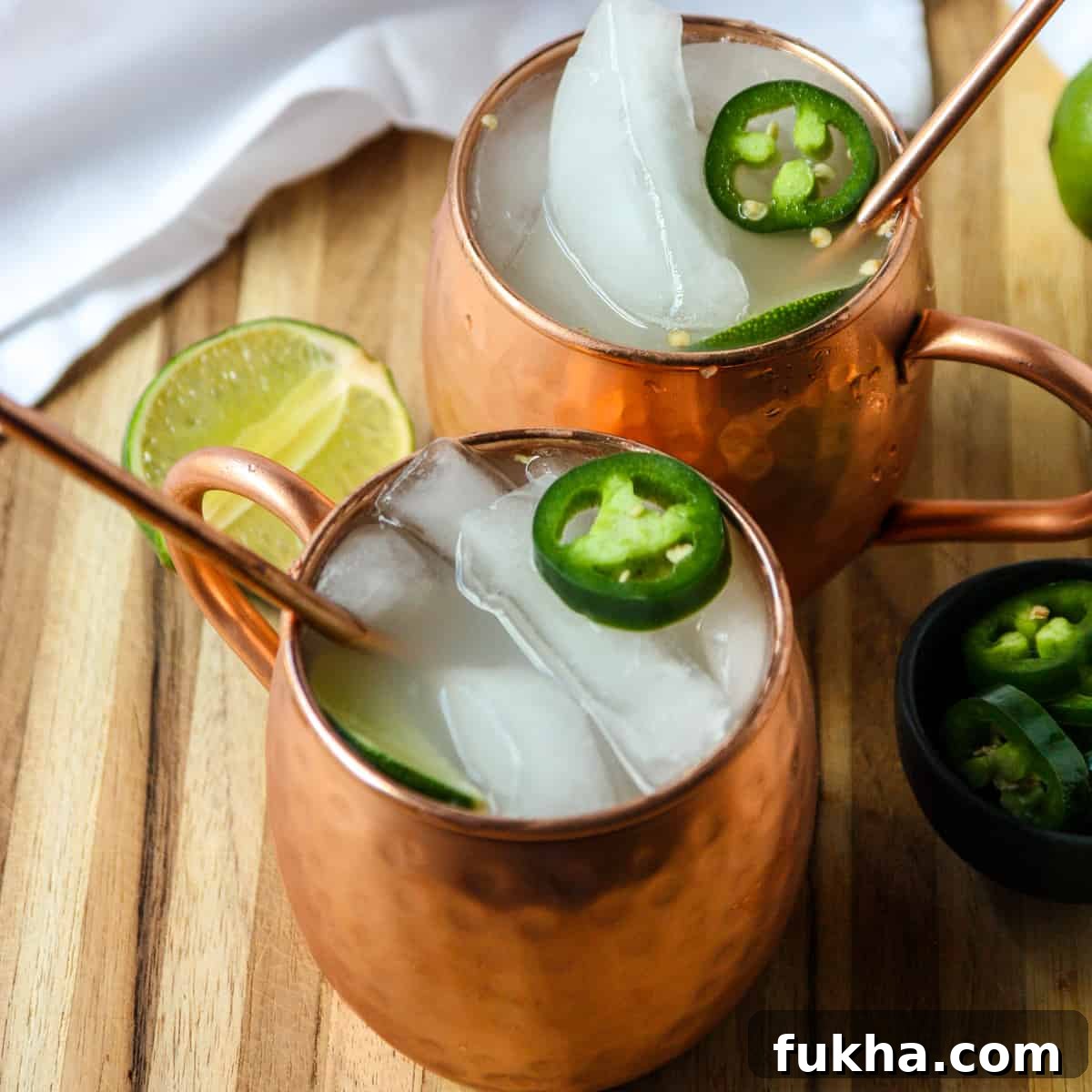 Two Mexican Mule cocktails in copper mugs garnished with lime.