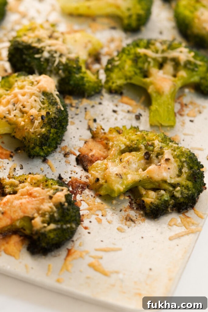 Crispy Smashed Broccoli with Parmesan 5 closeup shot of baked parmesan smashed broccoli florets on a baking sheet.