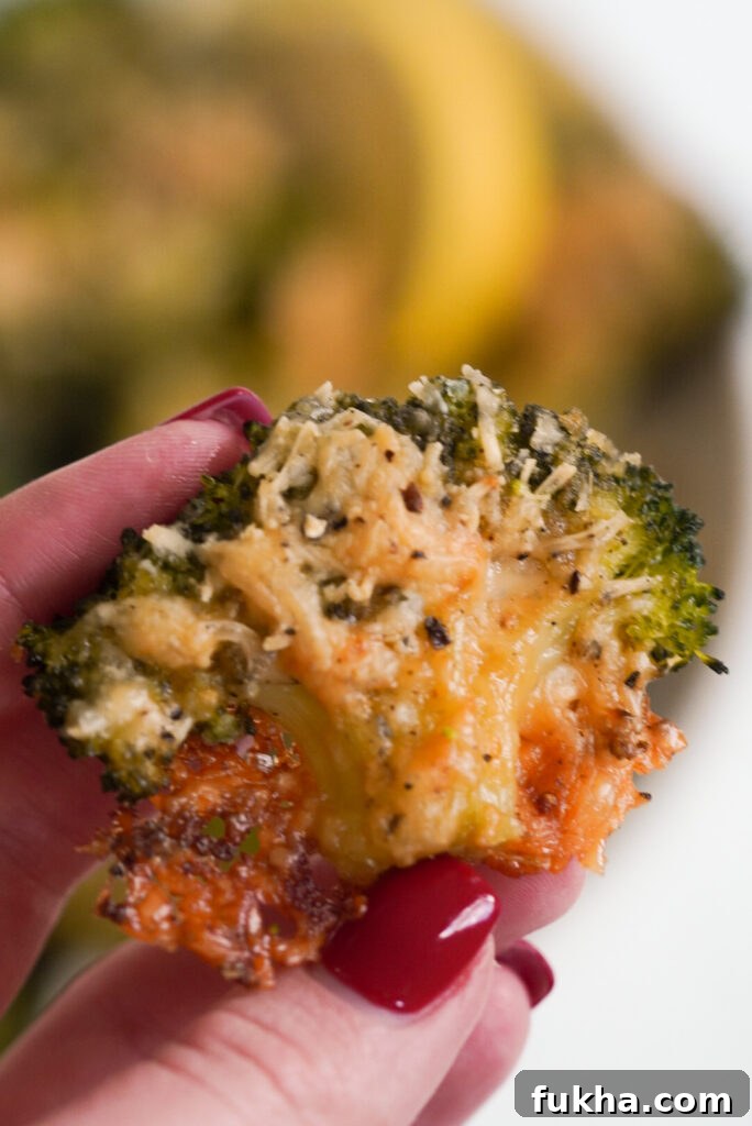 Crispy Smashed Broccoli with Parmesan 7 hand holding a floret of crispy, cheesy smashed broccoli parmesan.