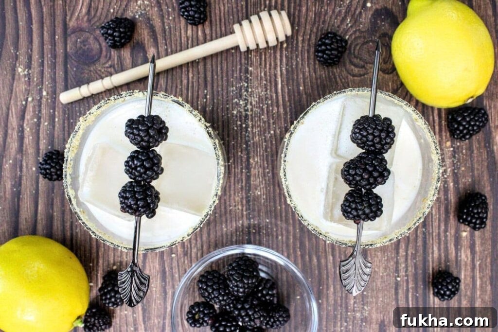 overhead view of two blackberry cobbler cocktails with fruit skewers