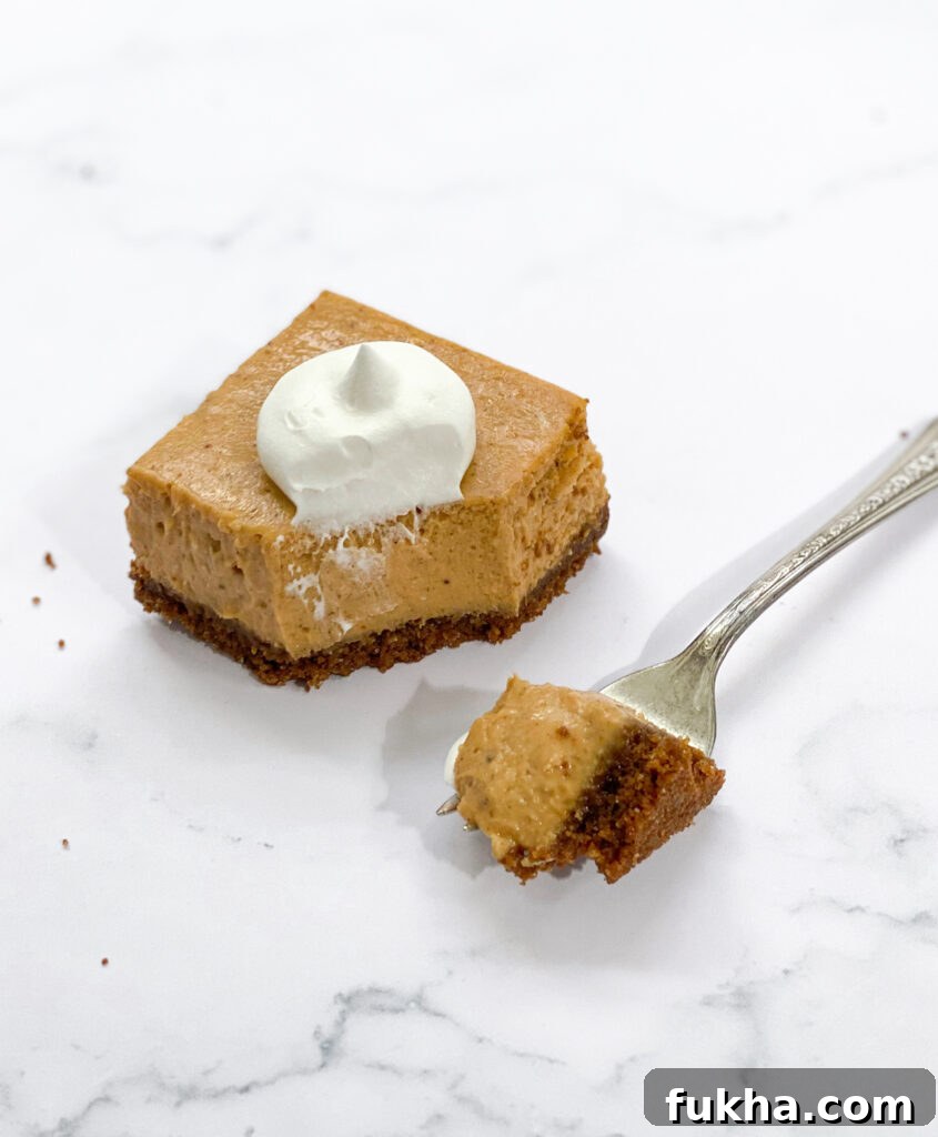 one pumpkin cheesecake bars with gingersnap crust and a fork with one bite
