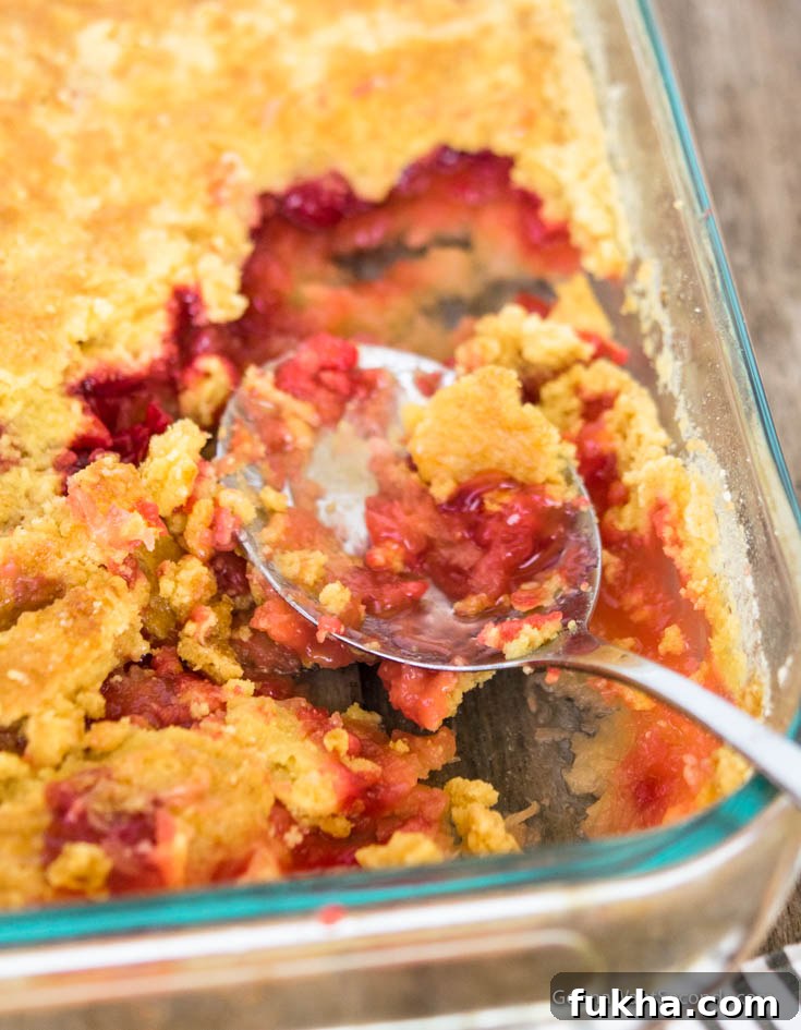 Scooping cherry pineapple dump cake in a casserole dish