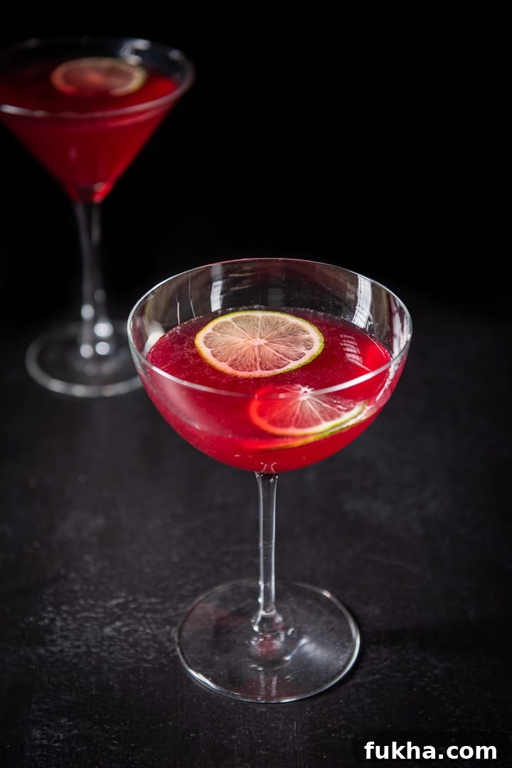 Pomegranate Cosmo Cocktail Recipe 2 Almost overhead view of the cosmo in the bowl glass with two lime wheels floating in them