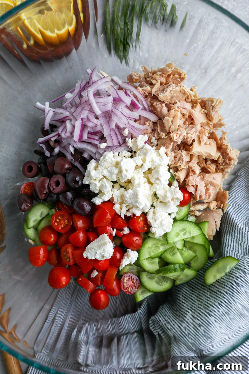 Mediterranean Tuna Salad with Feta and Lemon Vinaigrette 5 A large clear mixing bowl filled with canned tuna, sliced cucumber, tomaotes, kalamata olives, red onion and crumbled feta cheese