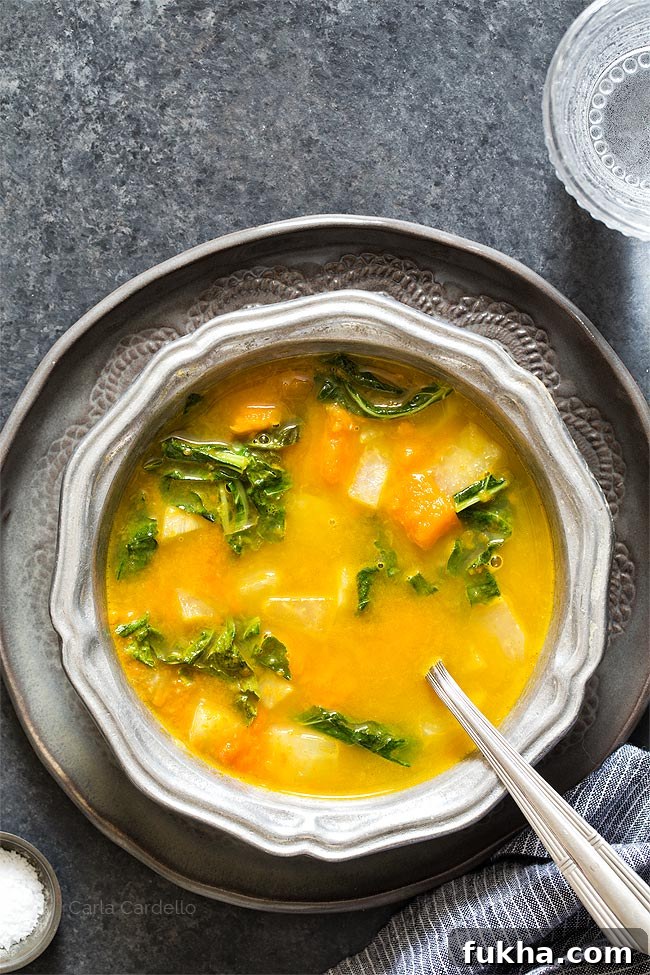 Kohlrabi Soup with Kohlrabi Greens in a silver ridged bowl on a dark gray plate