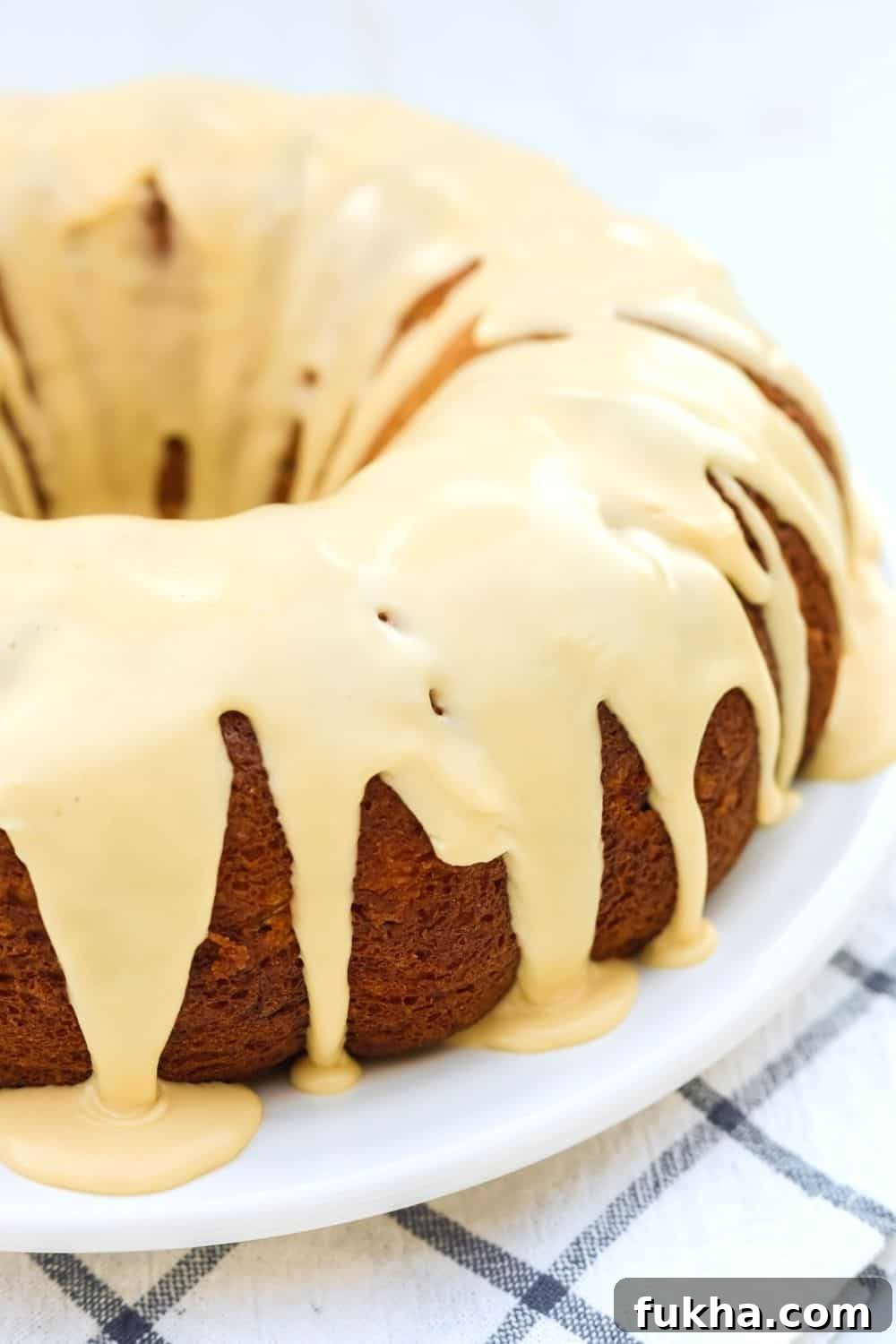 side view of a pear bundt cake made with a cake mix, on a white serving platter. The bundt cake is drizzled with a brown sugar icing.