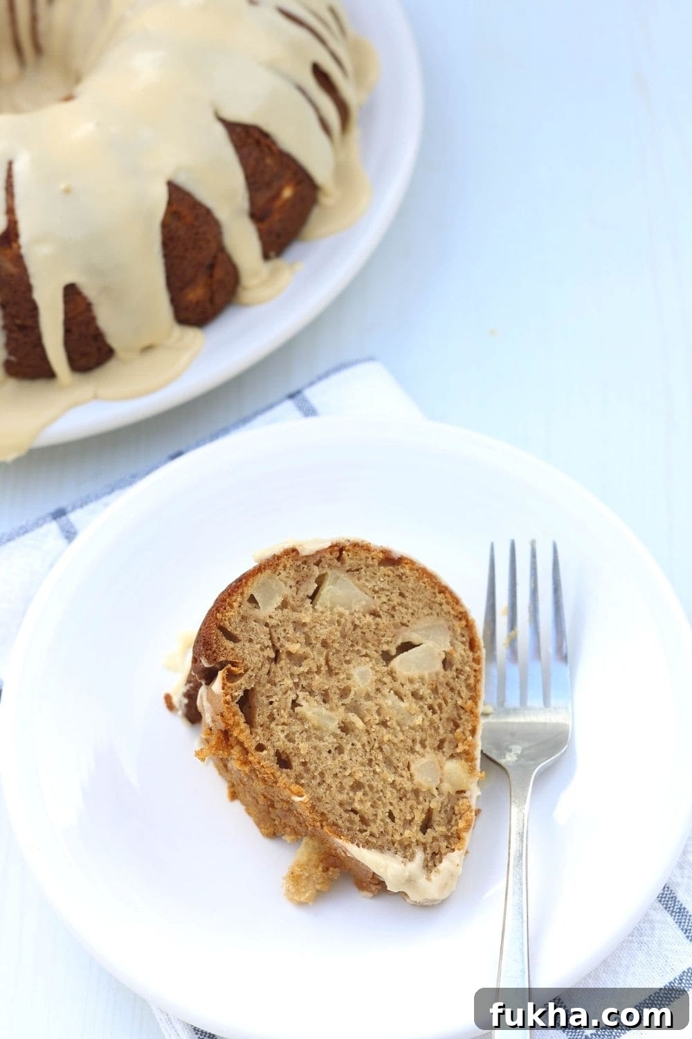 overhead view of a white plate with a fork and a slice of cake mix pear cake. The remaining bundt cake is in the background.