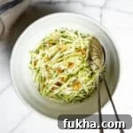 No mayo green apple slaw in a bowl with serving spoons.