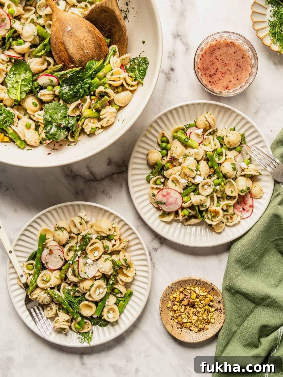 Bowls of spring pasta salad loaded with asparagus, radish, spinach, herbs and a tangy sumac honey dressing.