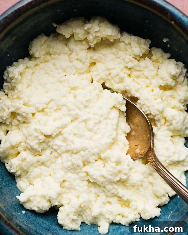 Homemade ricotta cheese in a blue bowl with a spoon.