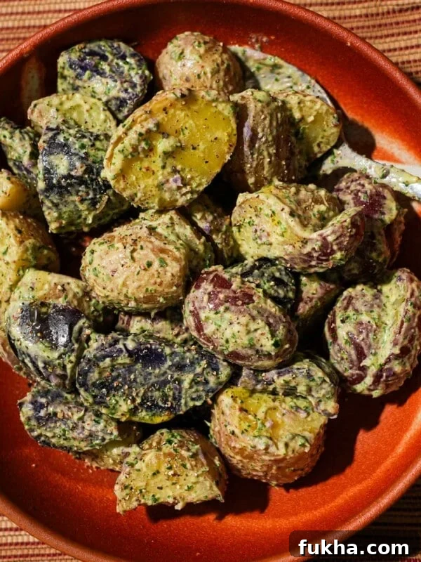 A bowl filled with potato salad with Chimichurri mayo with a spoon in it.