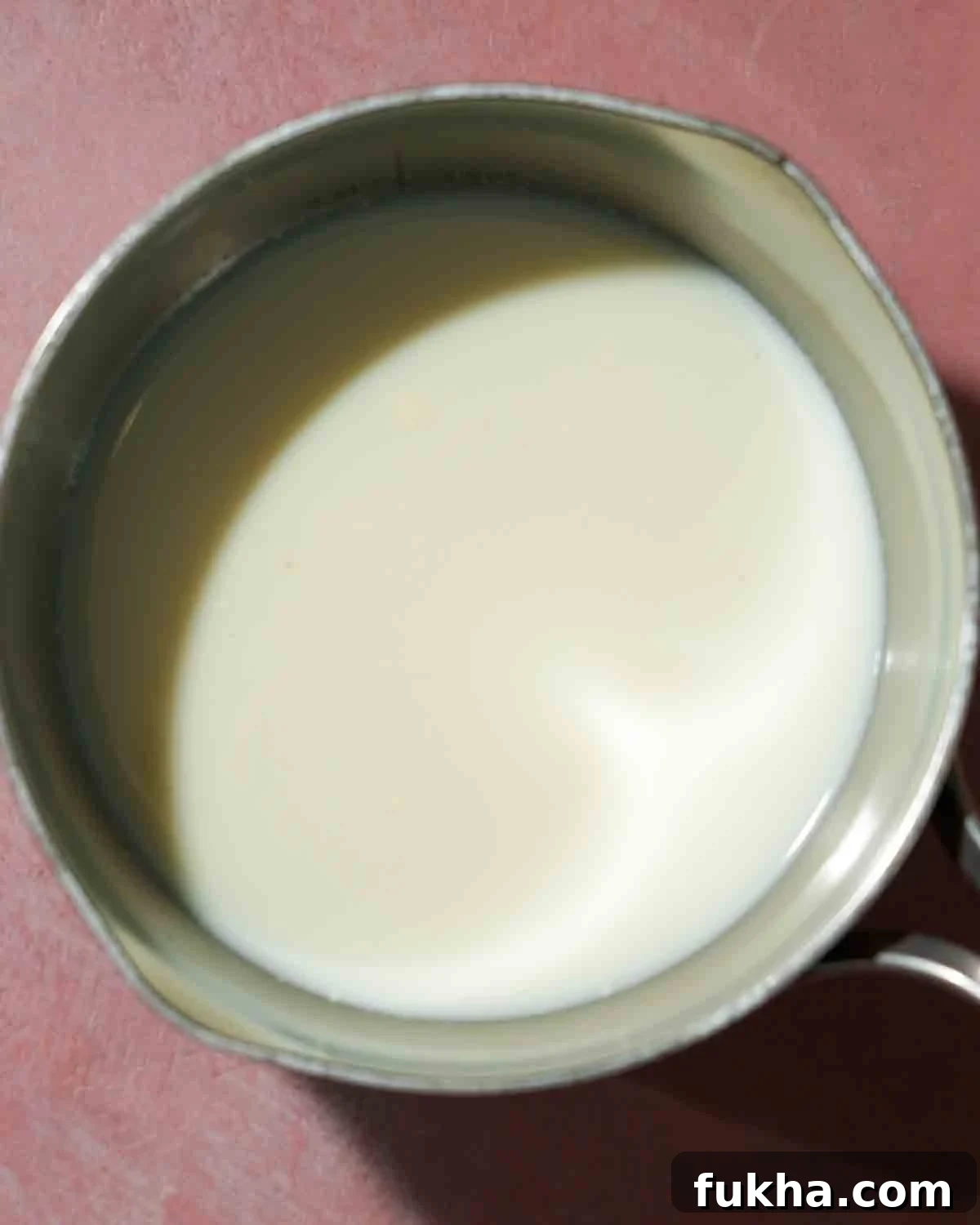 A bowl of milk being cook in a pot for homemade ricotta.