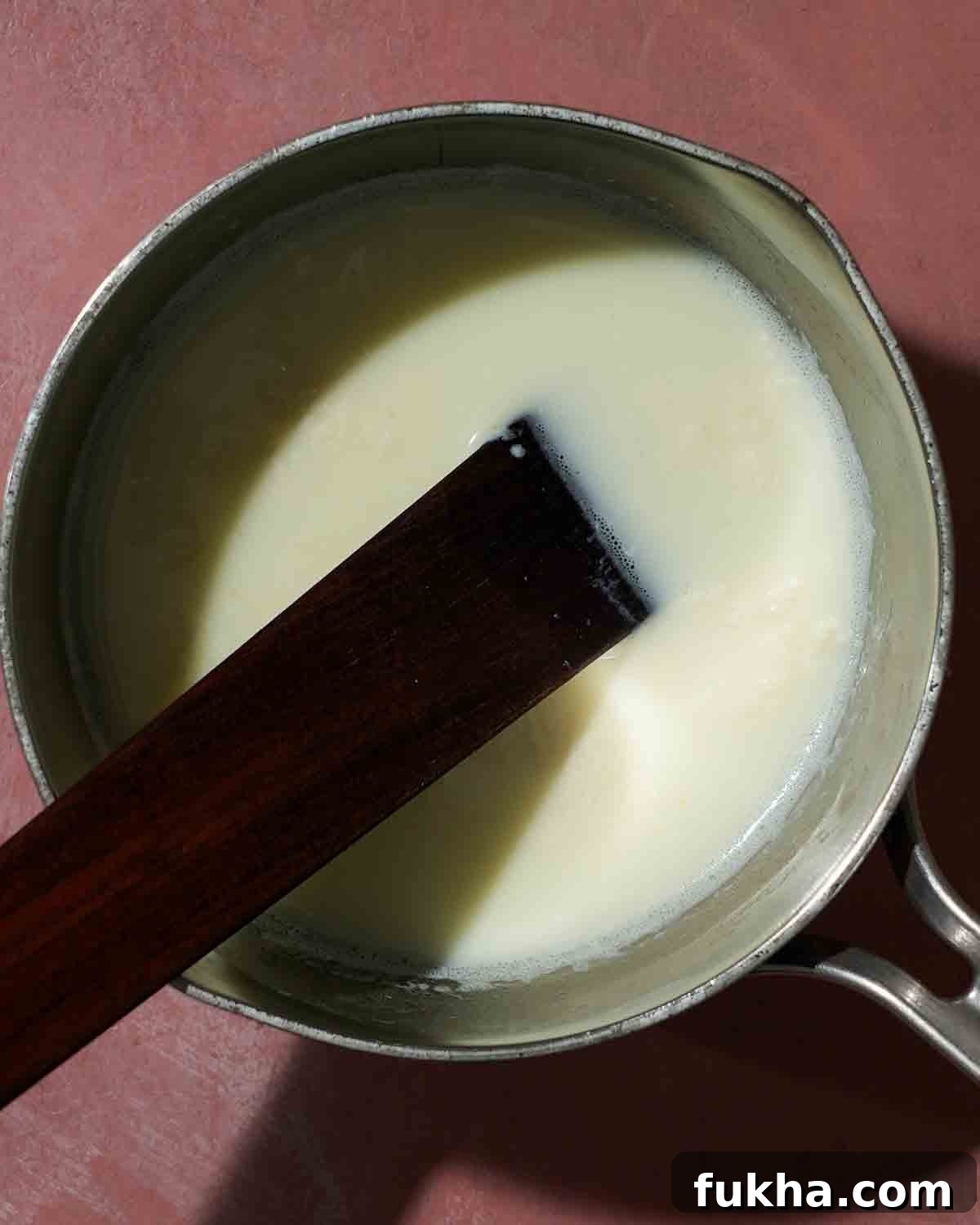 A pot of milk being curdled and mixed with lemon juice to make ricotta.