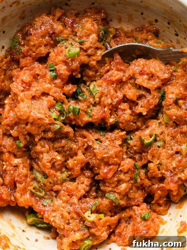 Spicy tuna with green onions in a bowl, mixed with a fork.
