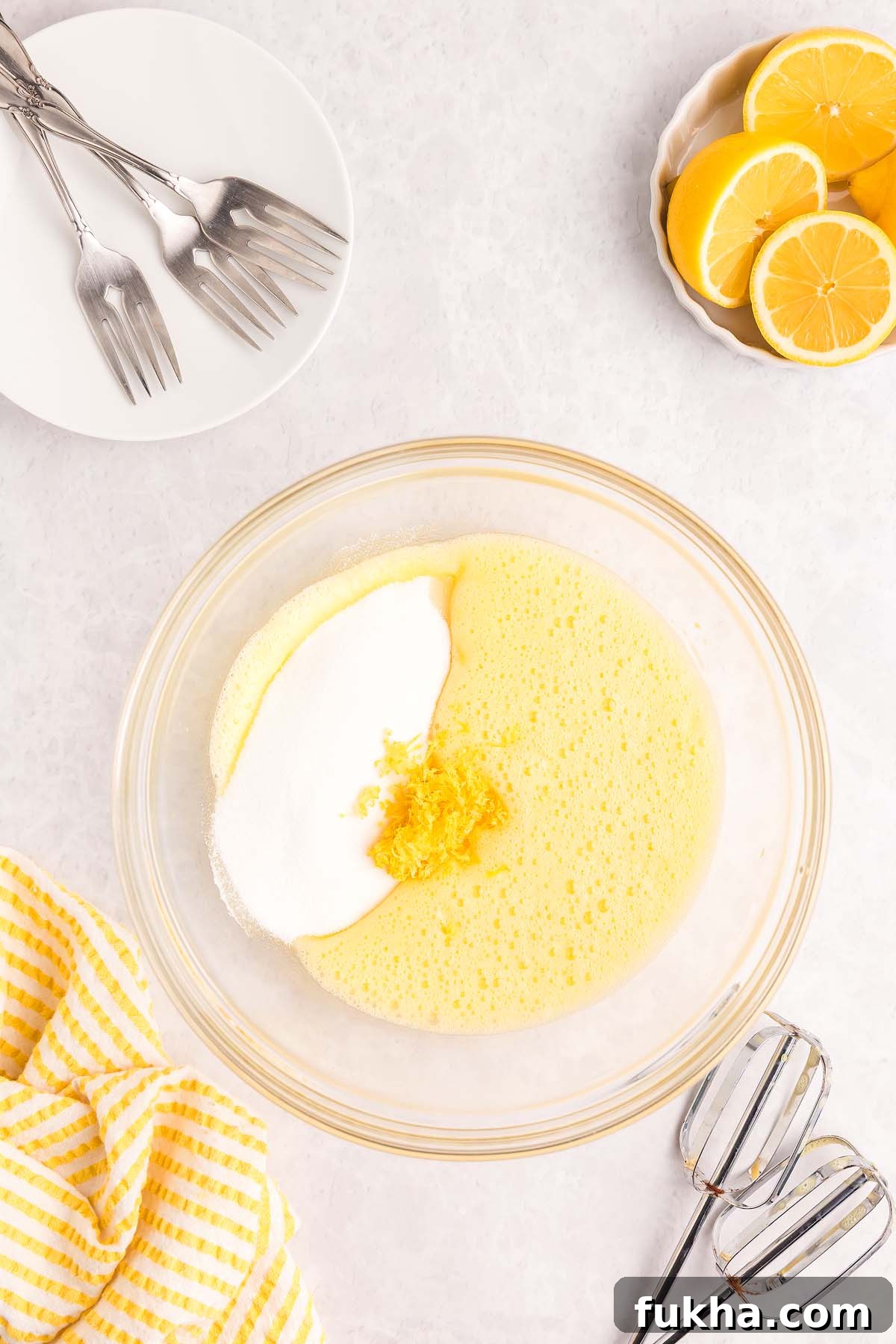 Zesty Lemon Swiss Roll Cake Recipe 14 Glass bowl with whisked eggs, sugar, and lemon zest.