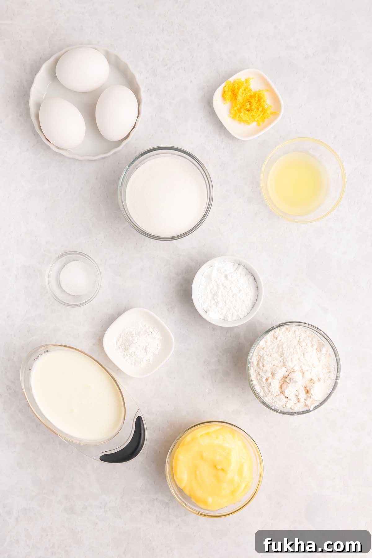 Zesty Lemon Swiss Roll Cake Recipe 6 Baking ingredients for a lemon roll cake arranged on a white surface.