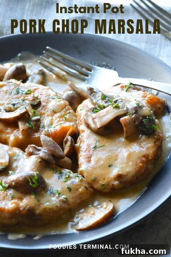 Creamy pork chops marsala on a black plate with a fork on the side