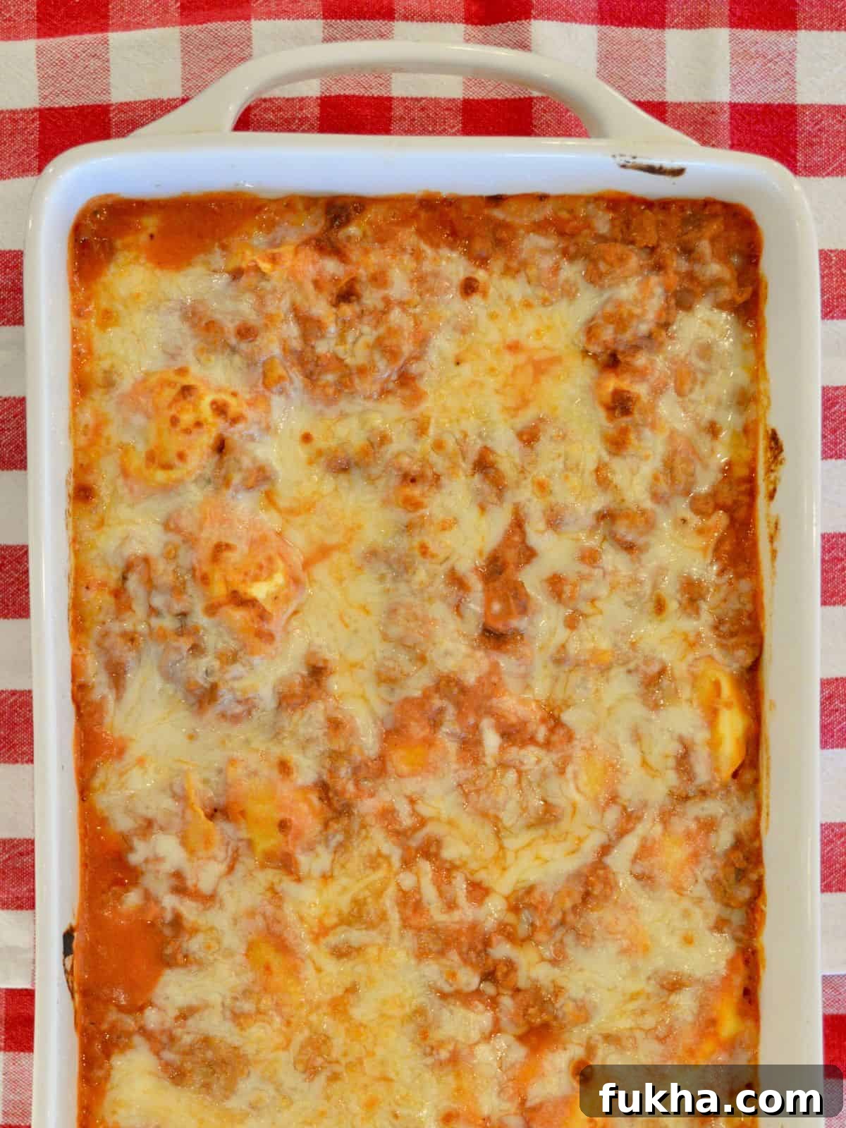 Cheesy Baked Tortellini Casserole with Meat Sauce 2 Baked tortellini casserole with a ground turkey meat sauce and ricotta cheese in a white casserole dish.
