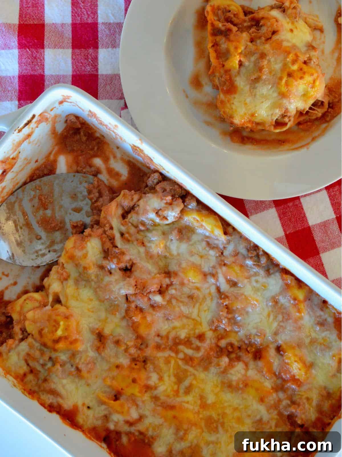 Cheesy Baked Tortellini Casserole with Meat Sauce 5 Overhead photo of baked tortellini casserole in a white casserole dish with a bowl of pasta next to it.