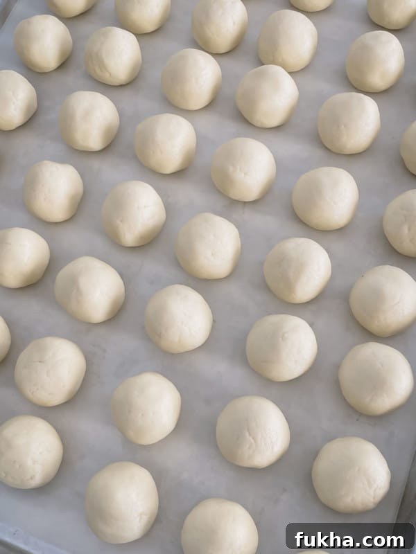 Snow White Roll Cake Recipe with Whipped Cream Filling 9 White cake balls on a baking sheet.